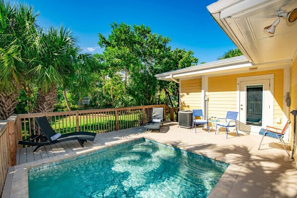 A backyard with a swimming pool, wooden deck, and outdoor furniture. - Charming Island Escape with Private Pool and Screened Lanai! (Anna Maria)