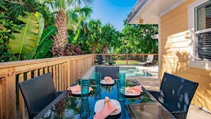 An outdoor patio with a glass table, chairs, and a pool. - Charming Island Escape with Private Pool and Screened Lanai! (Anna Maria)