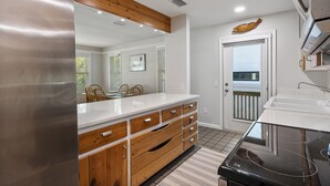 A modern kitchen with a stainless steel refrigerator, wooden cabinetry, and a black stove. - Charming Island Escape with Private Pool and Screened Lanai! (Anna Maria)