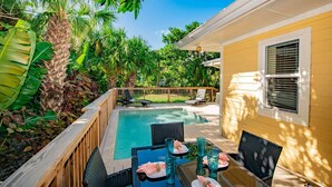 A backyard with a swimming pool, wooden deck, and outdoor furniture. - Charming Island Escape with Private Pool and Screened Lanai! (Anna Maria)