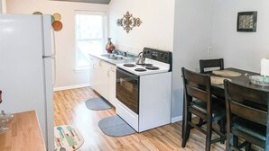 Una cocina compacta con refrigerador, estufa, pileta y mesa de comedor de madera con sillas.