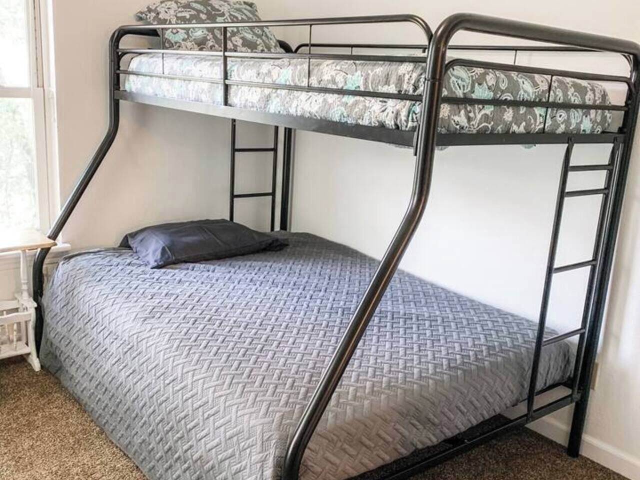 Un lit superposé avec un matelas à motifs, un oreiller et une structure en métal.