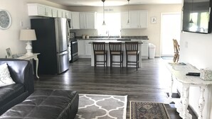 A modern kitchen with white cabinets, a stainless steel refrigerator, and a central island with bar stools. - Beautiful, recently built 6BR/ 4BA Home in Narragansett Pier!!! (Narragansett)