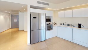 Une cuisine moderne avec des meubles blancs, un réfrigérateur en acier inoxydable, un four et un four à micro-ondes.
