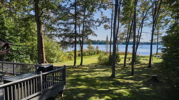 A deck with a view of a lake surrounded by trees.