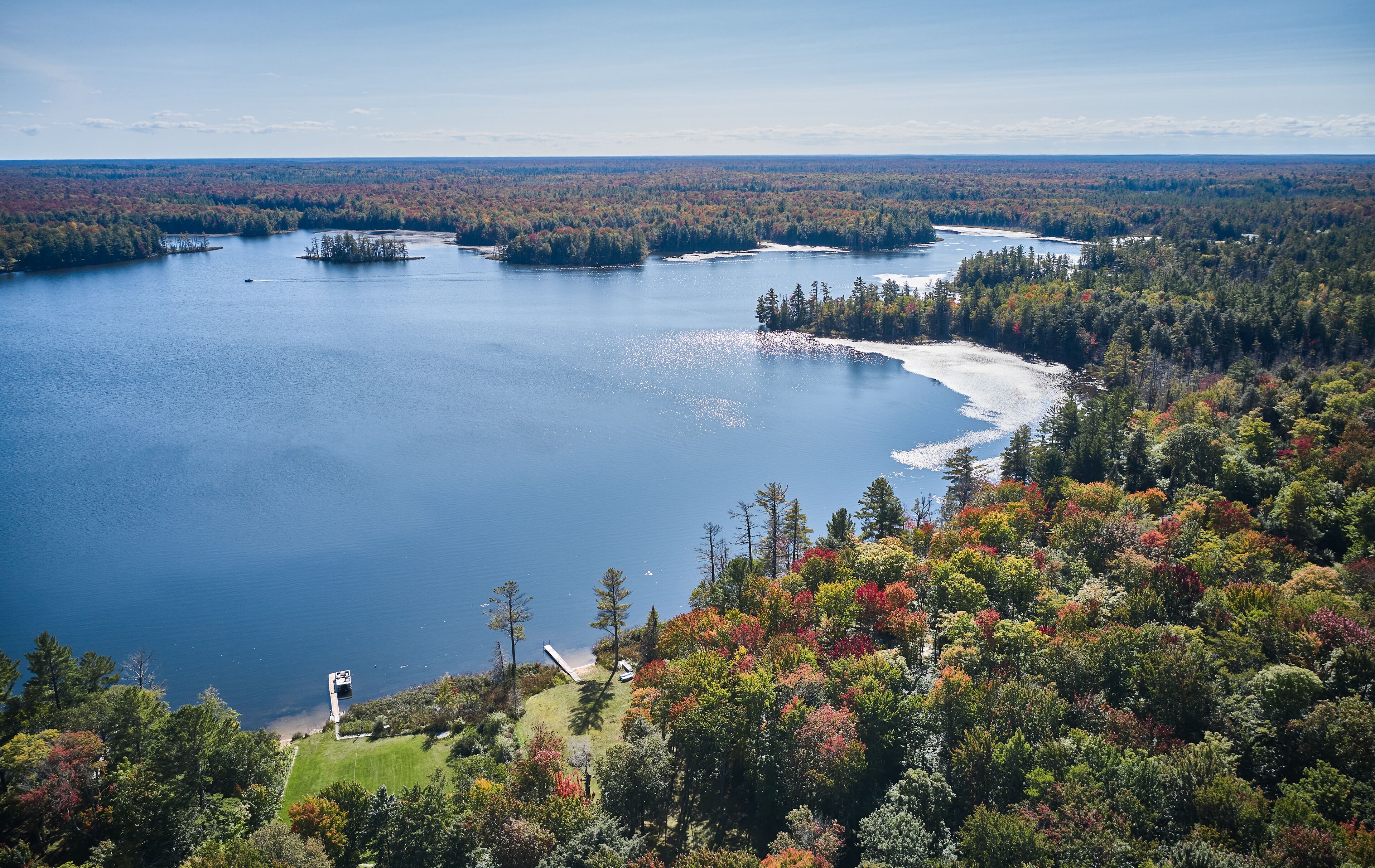 A lake surrounded by dense forest with a dock and a small building near the shore.