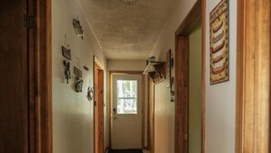 A narrow hallway with wooden doors, a ceiling light, and a patterned rug.