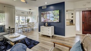 A modern living room with a dining area, a white cabinet, and a painting on the wall.
