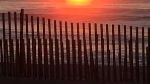 Tramonto sull'oceano con un recinto di legno in primo piano.