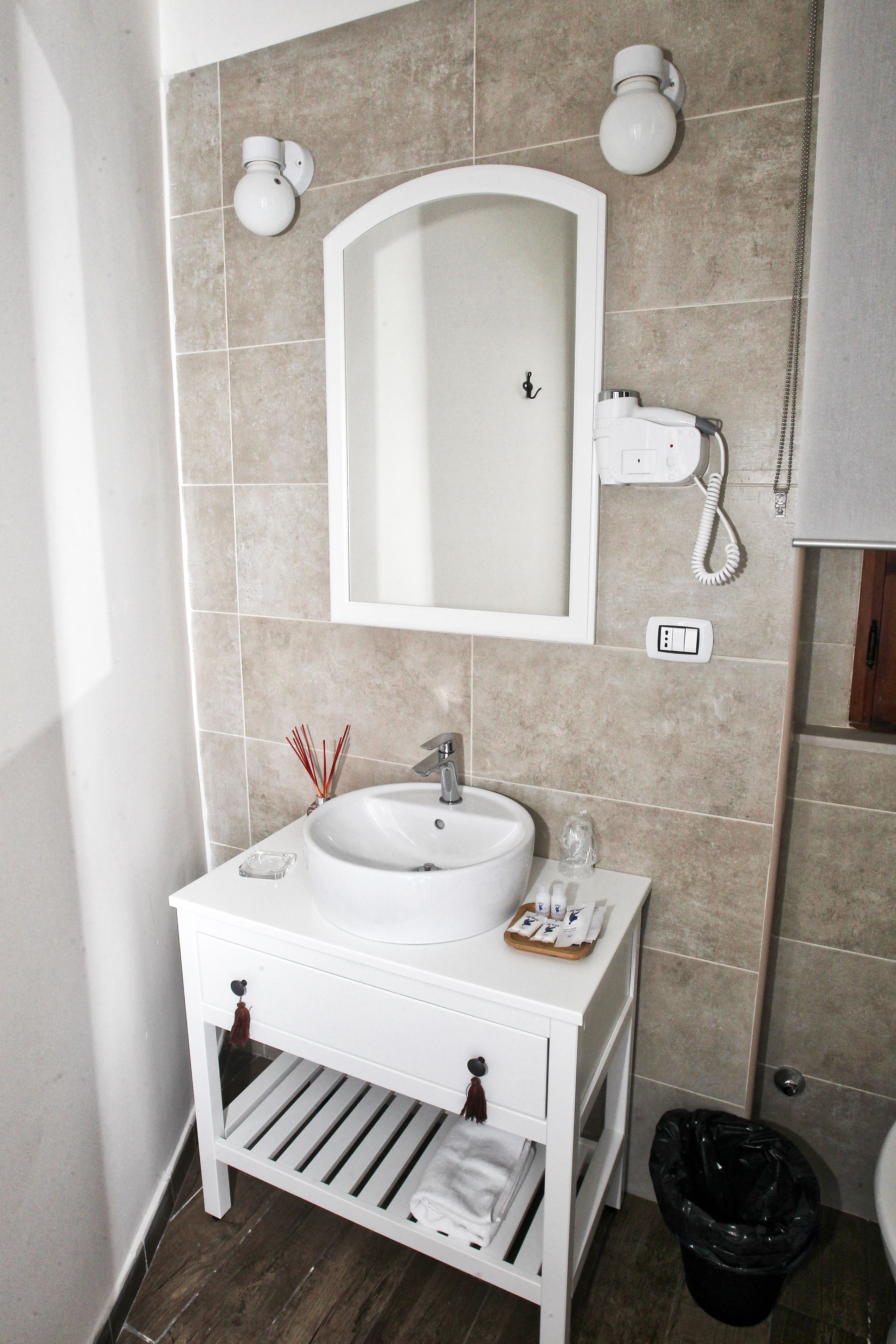 A bathroom with a white sink, mirror, and a telephone.