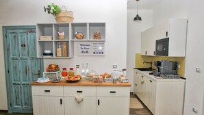 A kitchen with white cabinets, a wooden countertop, and a sign welcoming guests. - Villa al Mare B&B (Giovinazzo)