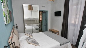 A bedroom with a large bed, a mirror, a small table, and a wall-mounted TV. - Villa al Mare B&B (Giovinazzo)