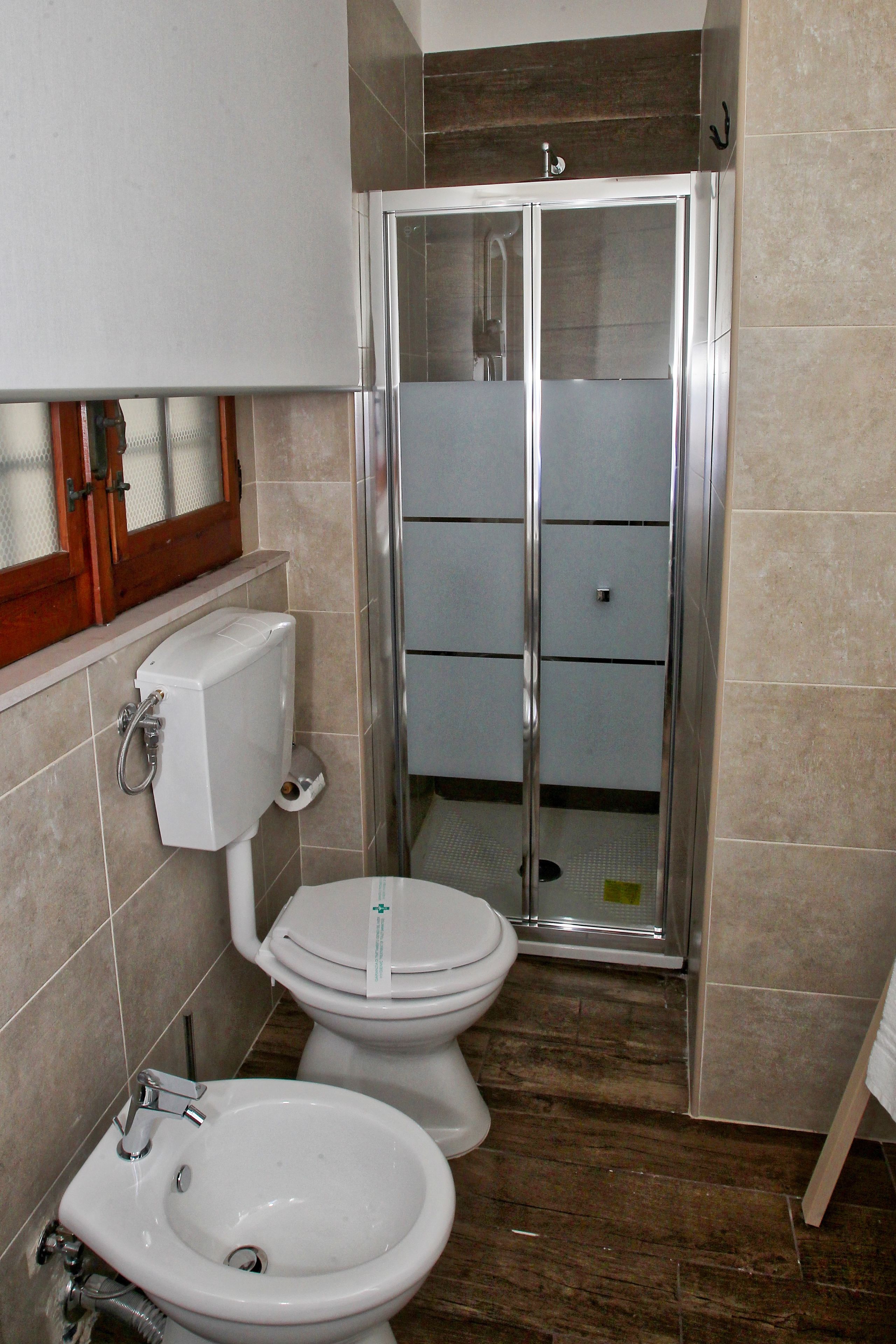 A bathroom with a toilet, bidet, and shower stall.