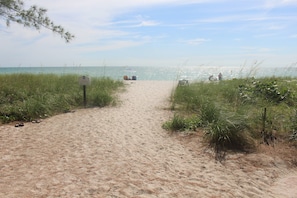 A sandy beach path leading to the ocean with a signpost and beach chairs. - Location...Location…Location! (Naples)