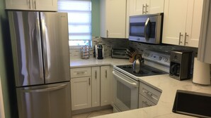 A modern kitchen with stainless steel appliances, white cabinets, and a tiled backsplash.