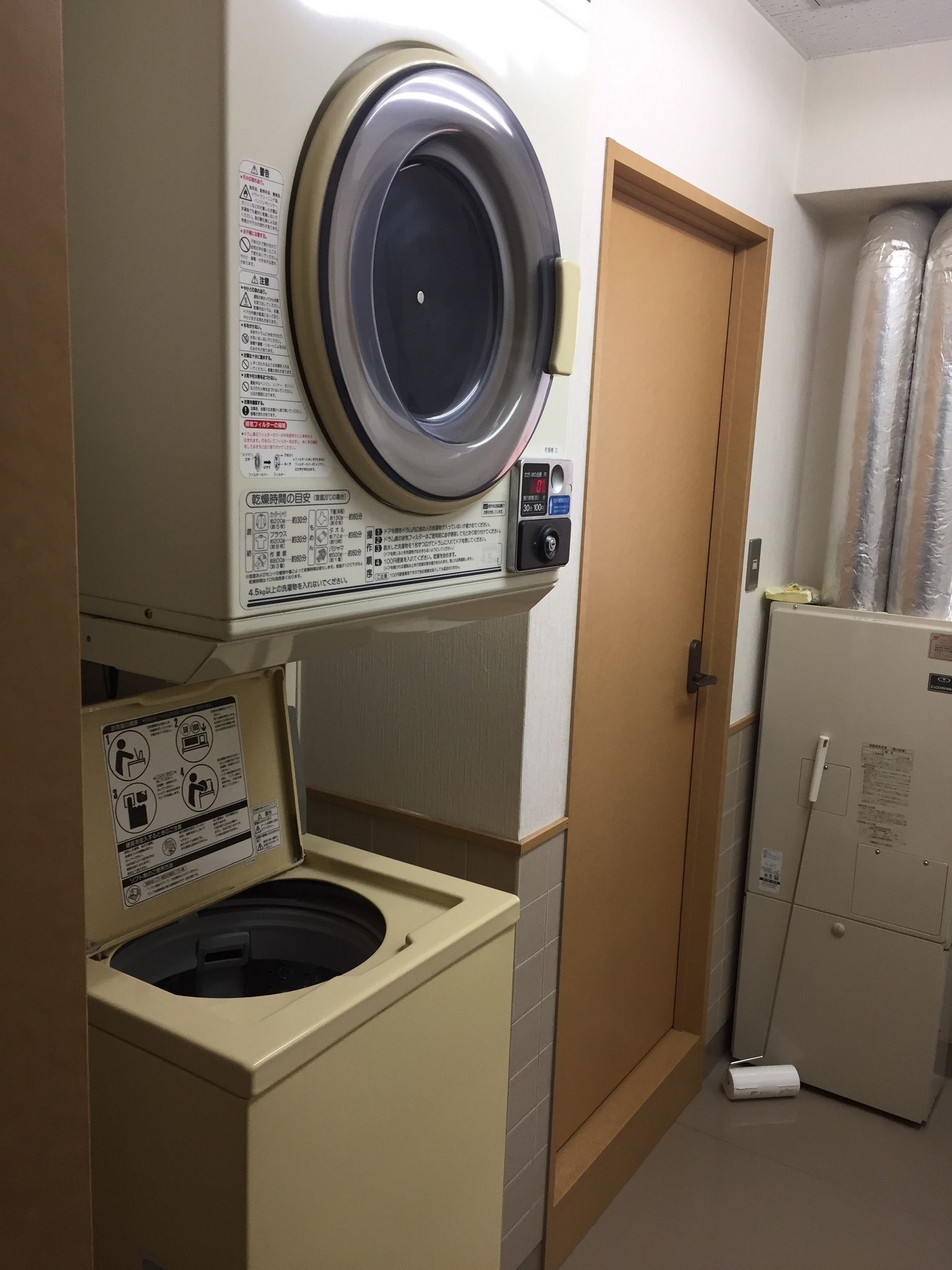 Une petite buanderie équipée d’un lave-linge à chargement frontal, d’un sèche-linge et d’un petit réfrigérateur.
