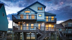 A two-story house with a balcony on the upper level, a staircase leading to the upper floor, and a deck area. - Beachfront Paradise of Texas 4br 3 1/2 baths (Galveston)