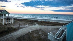 A beachfront property with a covered porch, a staircase, and a view of the ocean. - Beachfront Paradise of Texas 4br 3 1/2 baths (Galveston)