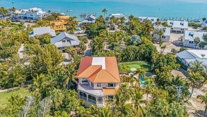 A coastal residential area with houses, a swimming pool, and a view of the ocean. - Luxury 5BR Gulf-View Home with Private Pool, Spa & High-Tech Entertainment (Captiva)