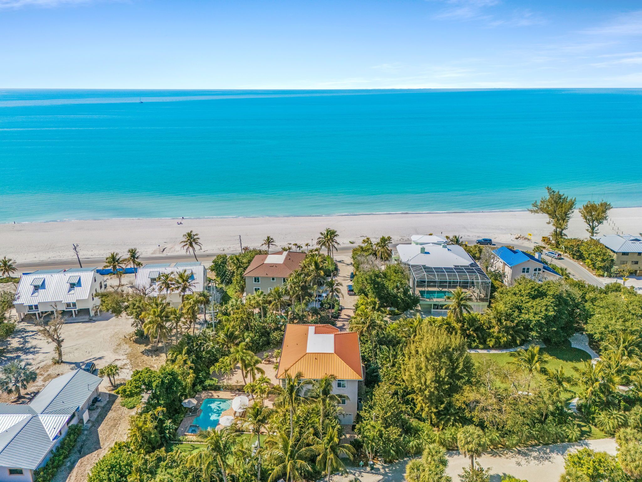 A coastal property with a swimming pool, beach access, and a view of the ocean.