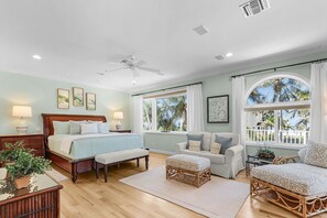 A bedroom with a bed, a sofa, a window with a view, and a ceiling fan.