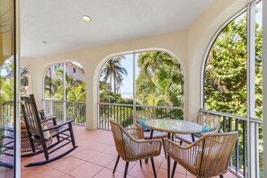 A balcony with wicker furniture, a rocking chair, and a table.