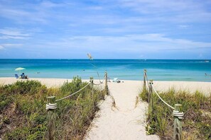 A beach path leading to the sea with a clear sky.