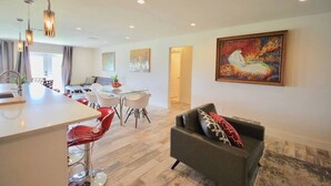 A modern living room with a dining area, a kitchen, and a hallway leading to another room. - Modern Waterfront Home with Hot Tub, Dock, Kayaks (New Port Richey)