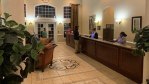 A lobby with a reception desk, a large plant, and a patterned floor.
