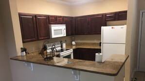 A kitchen with dark wooden cabinets, a white refrigerator, a microwave, and a stove.