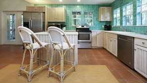 A kitchen with two wicker chairs, a refrigerator, an oven, and a dishwasher.