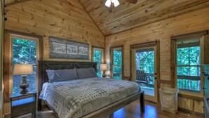 A wooden cabin bedroom with a bed, nightstands, a ceiling fan, and large windows. - Dog Friendly, PAVED 2 lane access, Aska Adventure Area, Minutes to Downtown (Blue Ridge)