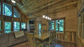 A wooden cabin interior with a dining table, chairs, a sofa, and large windows. - Dog Friendly, PAVED 2 lane access, Aska Adventure Area, Minutes to Downtown (Blue Ridge)