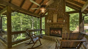 A wooden deck with a stone fireplace, rocking chairs, and a ceiling fan. - Dog Friendly, PAVED 2 lane access, Aska Adventure Area, Minutes to Downtown (Blue Ridge)