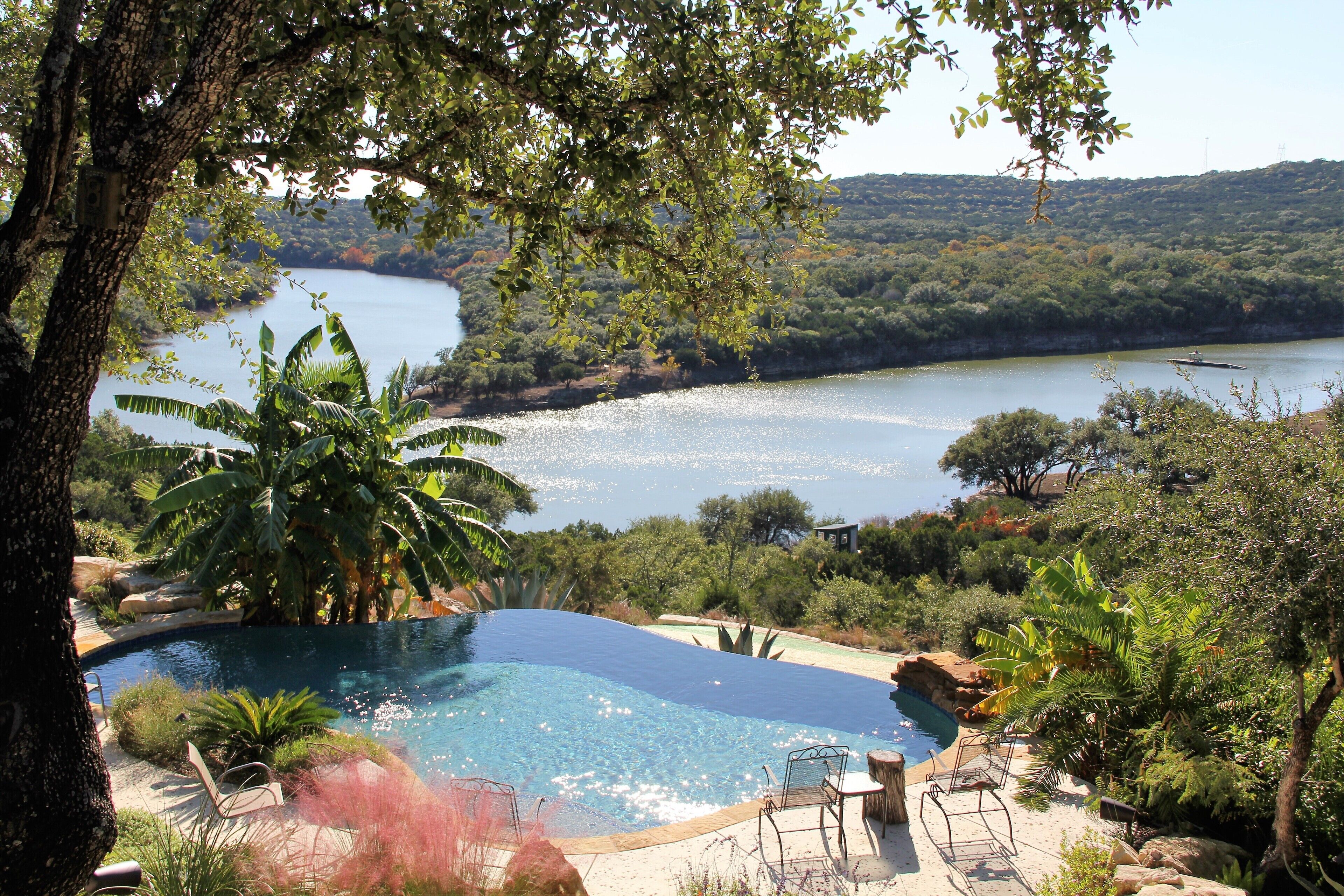 A swimming pool with a view of a lake and hills.