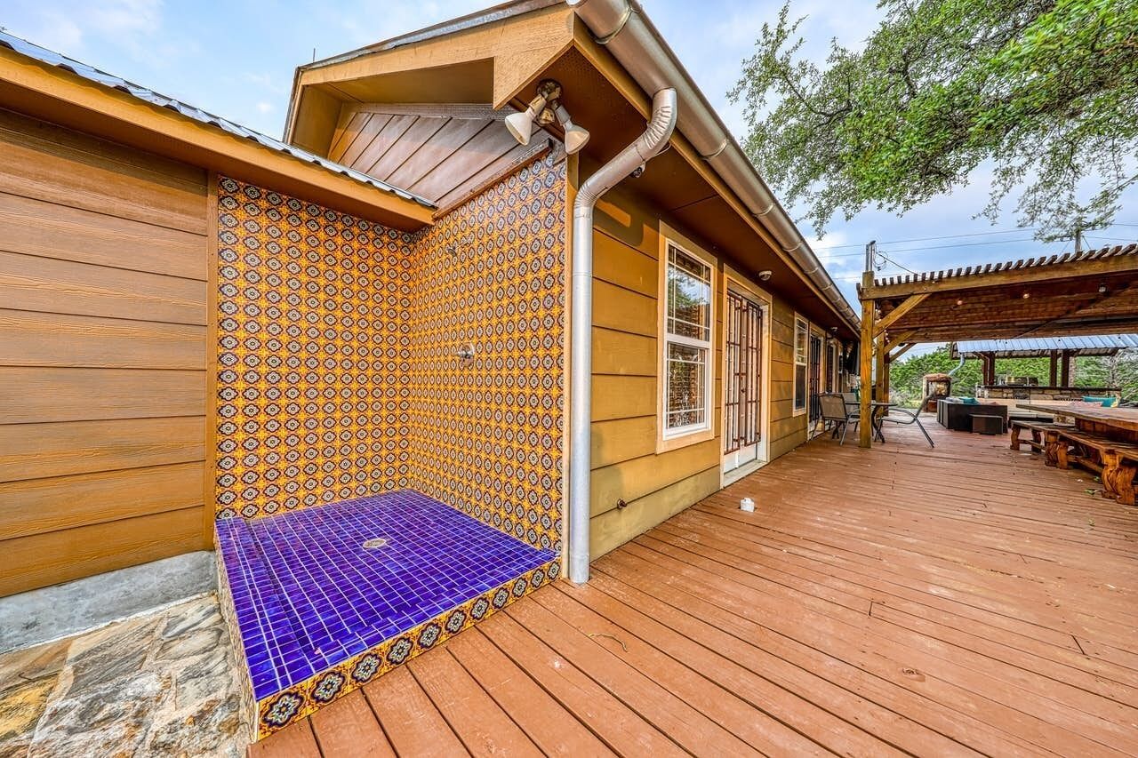 A wooden house with a tiled patio and a covered outdoor seating area.