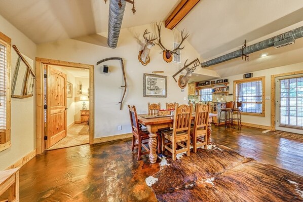 Un comedor amplio con una mesa y sillas de madera, rodeado de paredes decoradas con trofeos de animales.