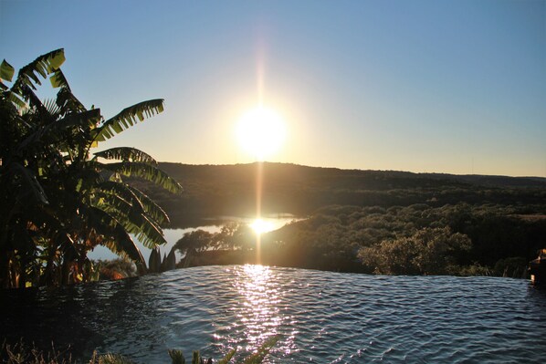 Un coucher de soleil sur une étendue d’eau, avec un paysage montagneux en arrière-plan.