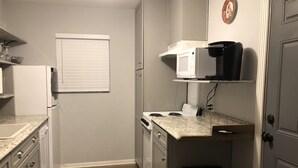 Una cocina funcional equipada con refrigerador, microondas, estufa y armarios.