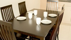 Une table à manger avec de l’assiette et des tasses blanches, entourée de chaises en bois.