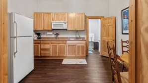 Une cuisine avec des meubles de rangement en bois, un réfrigérateur blanc, un four à micro-ondes et un ventilateur de plafond.