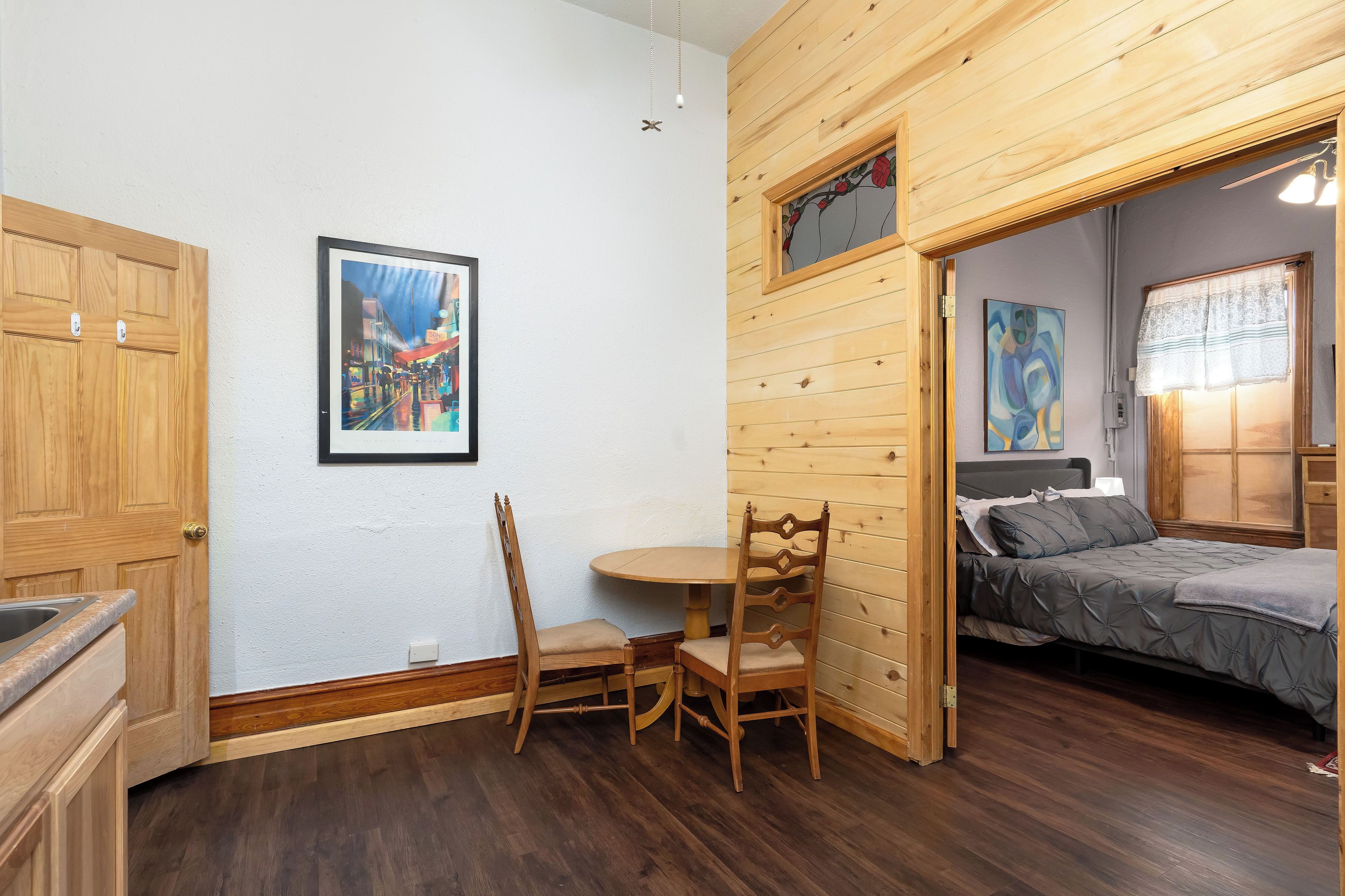 Una stanza con soffitto in legno, un letto, un tavolo da pranzo con sedie e un quadro appeso al muro.