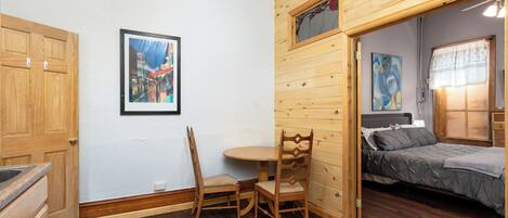 Una stanza con soffitto in legno, un letto, un tavolo da pranzo con sedie e un quadro appeso al muro.