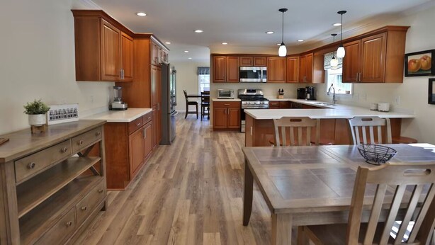 A modern kitchen with wooden cabinets, a central island, and a dining area.