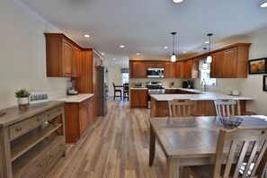 Una cocina moderna con armarios de madera, una isla central y un comedor.