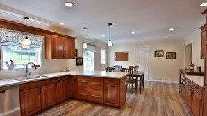 A spacious kitchen with wooden cabinets, a central island, and pendant lighting.