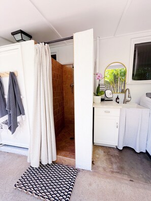 A bathroom with a shower, a sink, and a mirror.