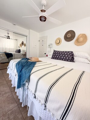 A hotel room with a bed, a ceiling fan, and a mirror.