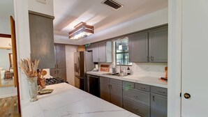 Una cocina moderna con encimeras de mármol, electrodomésticos de acero inoxidable y armarios grises.