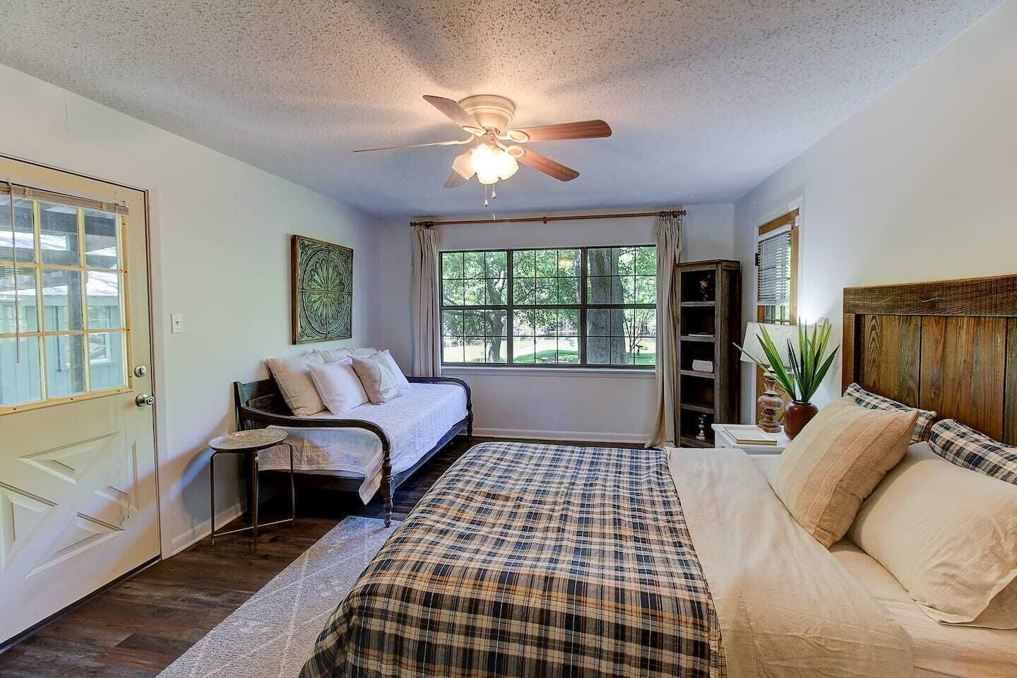 Une chambre à coucher avec un lit, une chaise, un ventilateur de plafond et une fenêtre.